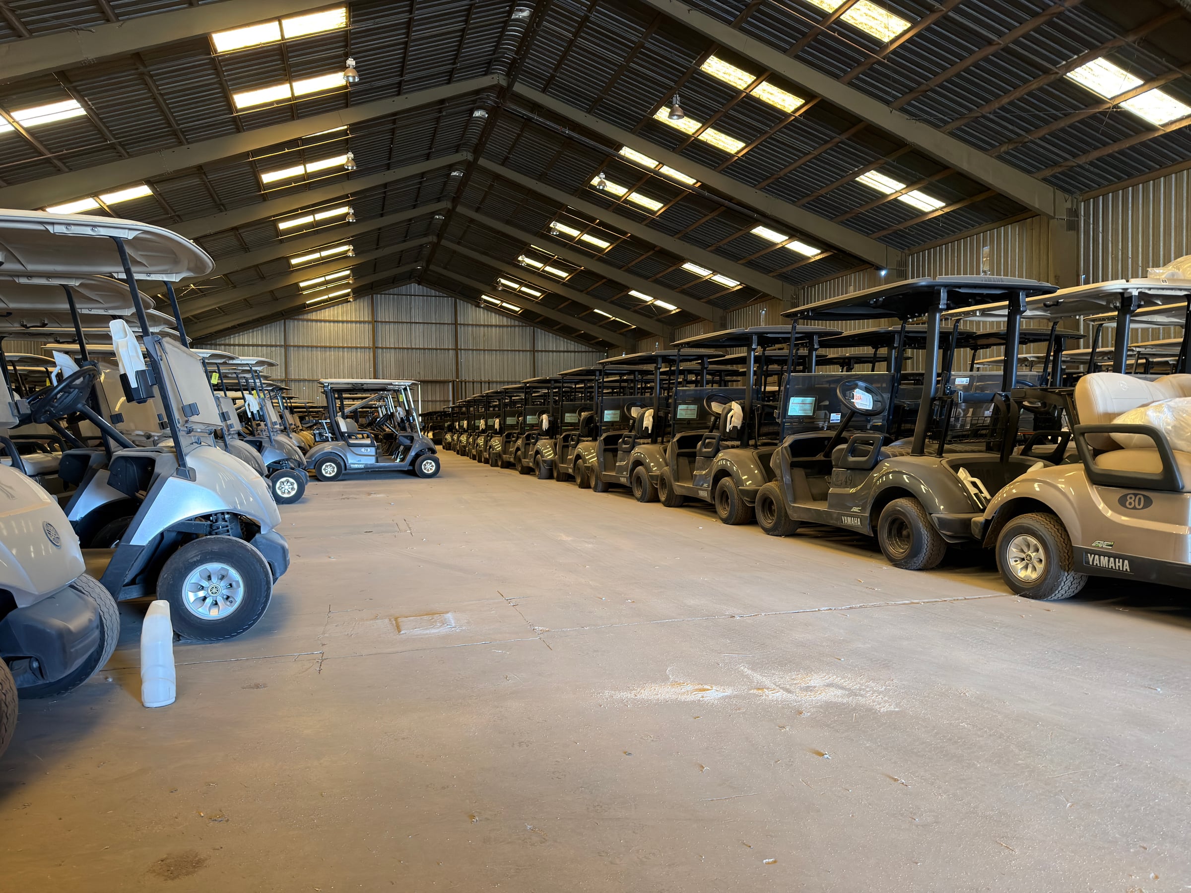 Long rows of golf carts organized inside a large warehouse.